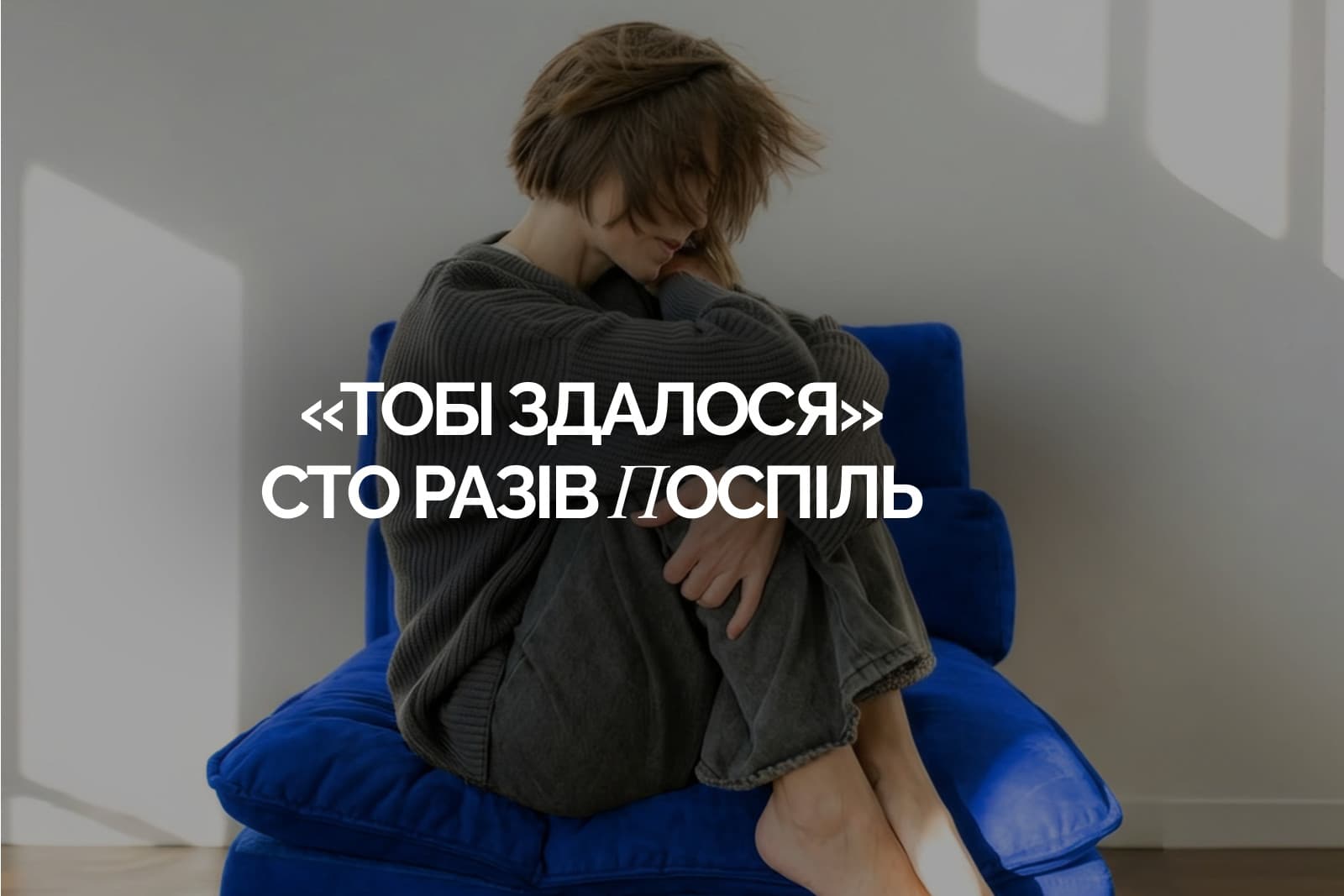 Жінка в сірому светрі сидить на синьому кріслі, обійнявши коліна й сховавши обличчя, напис «Тобі здалося» сто разів поспіль