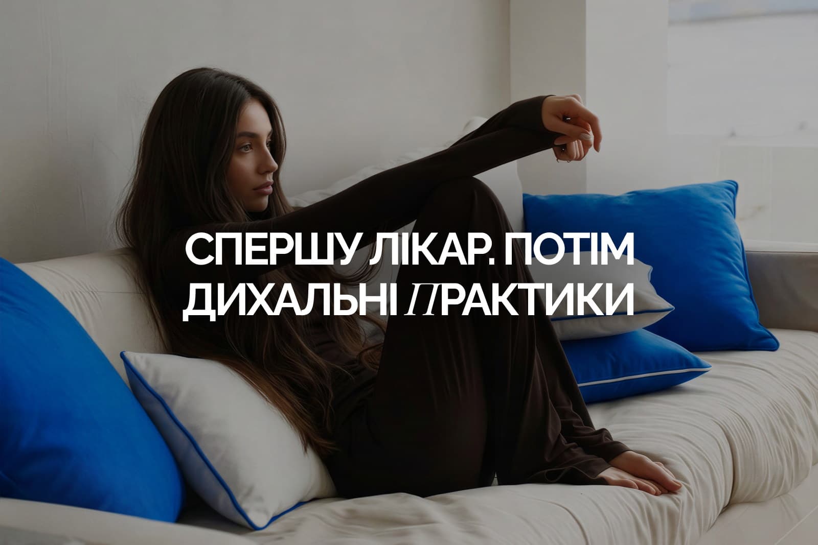 Жінка сидить на дивані, обійнявши коліна, і дивиться вбік